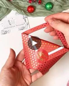 two hands are holding a red origami box