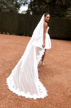 a woman in a white wedding dress standing on a tennis court with her veil over her head