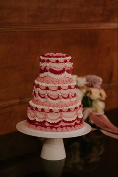 a red and white tiered cake sitting on top of a table