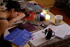 a woman sitting at a table with books and candles on top of it next to her