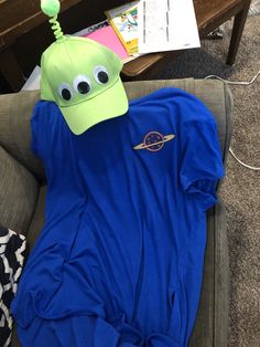 a blue shirt with a green alien hat on it sitting on top of a couch