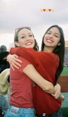 two girls hugging each other at a baseball game