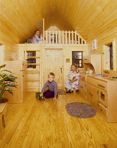 two children are playing in the loft of a tiny cabin with wood floors and walls