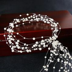 a bridal headpiece with pearls on it and a wooden box in the background