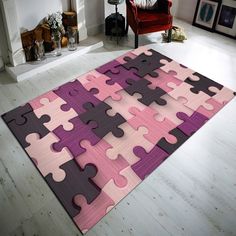 a pink and purple rug with puzzle pieces on it in front of a fire place