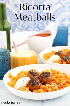 two white bowls filled with rice and meatballs on top of a table next to a bottle