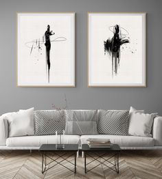 two black and white paintings on the wall above a couch