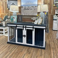 a dog kennel in the middle of a room with wood flooring and furniture