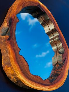 a mirror that is on the side of a wooden wall with blue sky in the background