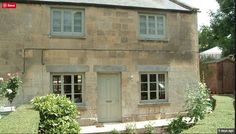 an old stone house with two windows on the front and one door is open to let in light