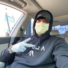 a man wearing a face mask and gloves in the back seat of a car with his hand up