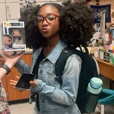 a woman holding up a cell phone in front of a girl with curly hair and glasses