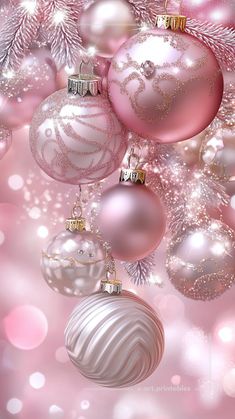 pink and white christmas ornaments hanging from a tree with snowflakes in the background