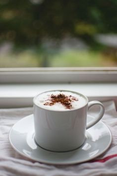 a cup of hot chocolate on a saucer next to a window