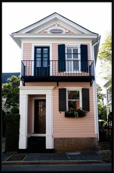 a pink house with black shutters on the front and windows in the second story