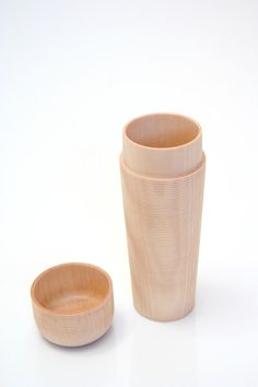 two wooden cups sitting next to each other on a white surface with one cup in the middle