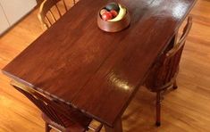 a wooden table with chairs around it and an apple bowl on the top of it