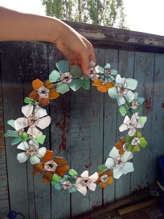 a wreath made out of paper flowers is being held by a person's hand