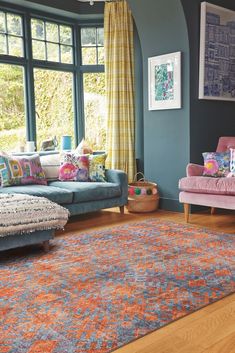 a living room filled with furniture and a rug on top of a hard wood floor