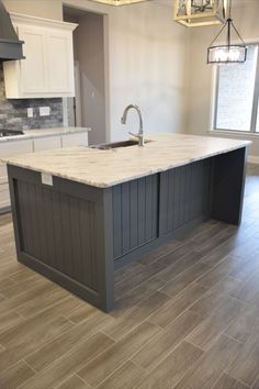 an empty kitchen with white cabinets and marble counter tops, along with gray tile flooring