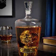 a skull shaped glass sitting on top of a table next to a bottle of alcohol