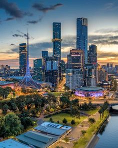 the city skyline is lit up at night, with tall buildings in the background and water below