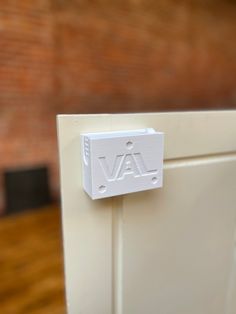 a close up of a white door handle with the word va on it and a brick wall in the background