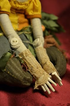 an old doll is sitting on the floor with its hands and feet covered in fabric