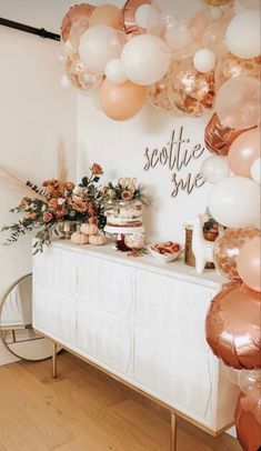 a table topped with lots of balloons next to a white wall and wooden flooring