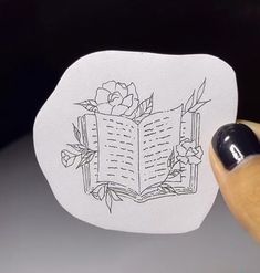 someone is holding an open book with a rose on it and the pages have been drawn