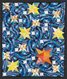 a blue and yellow quilt with stars in the center on top of it, surrounded by swirls