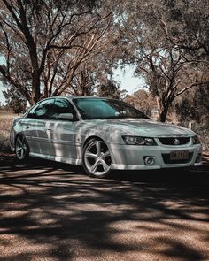 a silver car parked in front of some trees