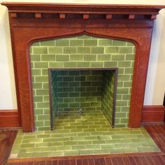 an old fireplace with green tiles and wood