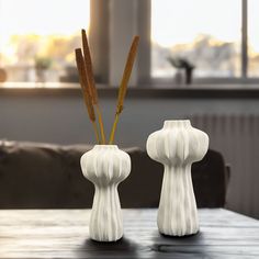 two white vases sitting on top of a wooden table