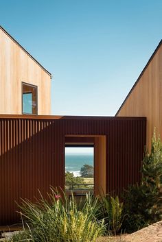 two wooden buildings sitting next to each other on top of a hill near the ocean