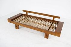 a wooden bed frame sitting on top of a white floor covered in wood slats