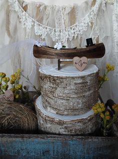 a cake with a wooden heart on top sitting in front of some flowers and decorations