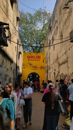 many people are walking through an alley way with graffiti on the walls and in between them is a yellow sign that reads sarolin market