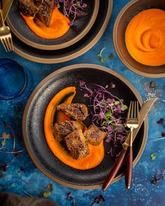 two plates filled with food on top of a blue table next to utensils