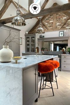 a kitchen with an island and stools in the center, surrounded by wooden beams