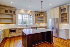 a large kitchen with wooden floors and white cabinetry on the walls, along with an island in the middle