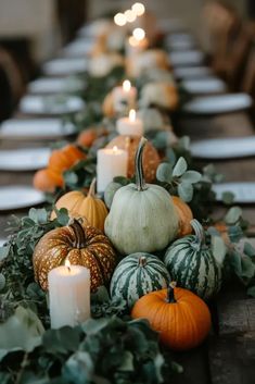 a long table topped with lots of pumpkins and greenery