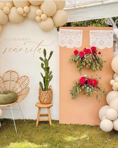 an outdoor event with balloons and flowers on the wall, chairs and tables in front of it