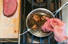 a person is cooking meat in a pan on the stove with a wooden cutting board next to it