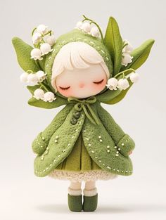 a little doll is dressed in green and has flowers on it's head, while she