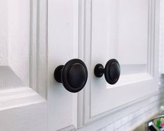 a close up of two black knobs on a white cabinet