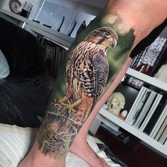 a tattoo on the leg of a person with an eagle sitting on top of a tree branch