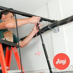 a man on a ladder working on an air conditioner