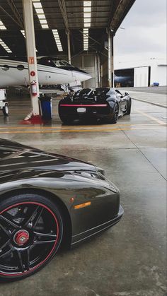 two black sports cars parked next to each other in front of an air force jet