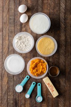 the ingredients to make pumpkin pie laid out on top of a wooden table, including eggs, flour and butter